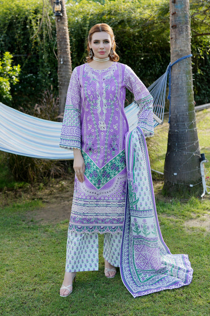 Woman in a purple and white traditional outfit standing outdoors with trees and a hammock in the background.