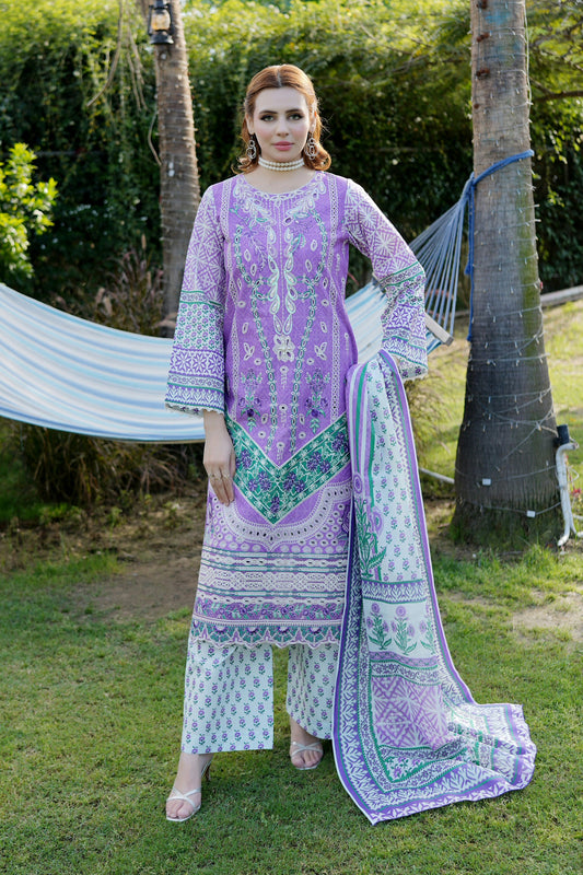 Woman in a purple and white traditional outfit standing outdoors with trees and a hammock in the background.